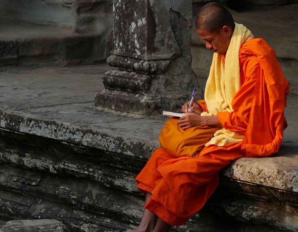 Buddhist Monk sitting and writing at Angkor Thom Temple, Siem Reap