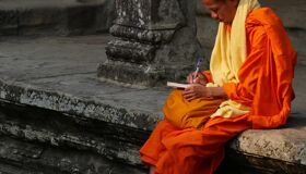 Buddhist Monk sitting and writing at Angkor Thom Temple, Siem Reap